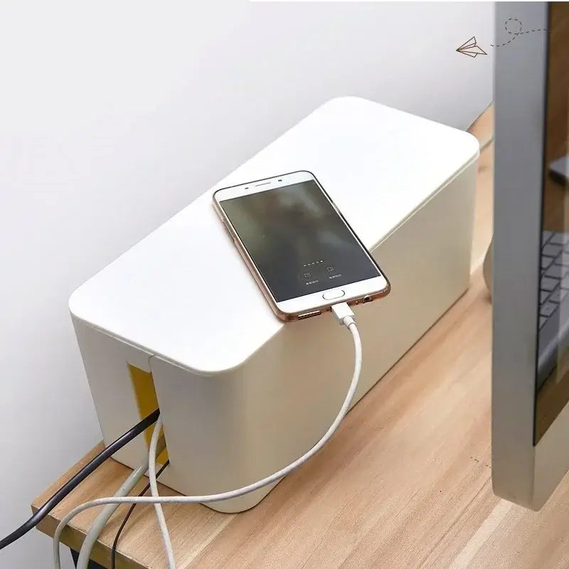 Boîte de rangement pour prises et câbles sur un bureau avec un smartphone en charge