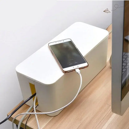 Boîte de rangement pour prises et câbles sur un bureau avec un smartphone en charge