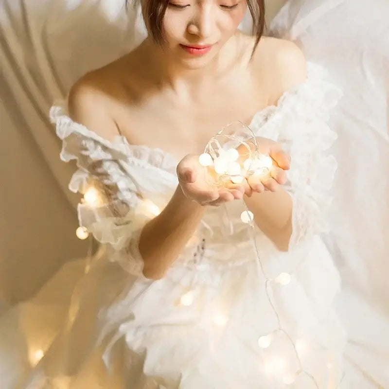 Woman holding LED ball string lights, enhancing the room's ambiance with soft, enchanting illumination for versatile decor.