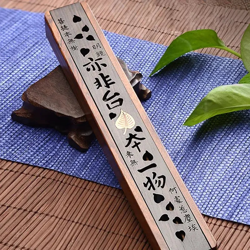 Boîte à encens sculptée en bois d'ébène et buis, décor zen asiatique sur napperon bleu avec feuilles vertes